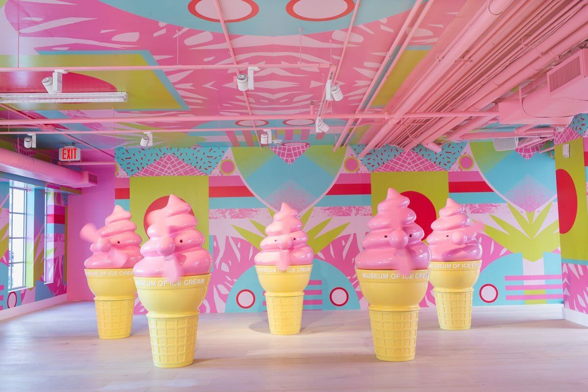 Large pink ice-creams with fans in a colourful room.