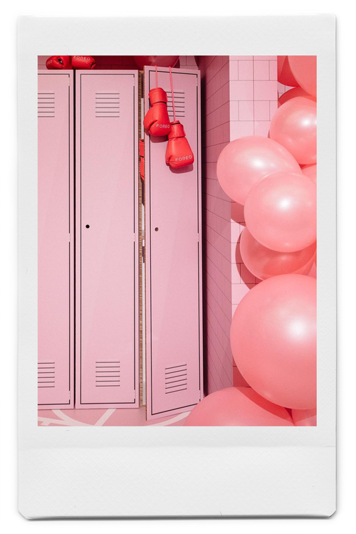 Large pink lockers with red boxing gloves hanging over the top made out of Re-Board surrounded by pink balloons.