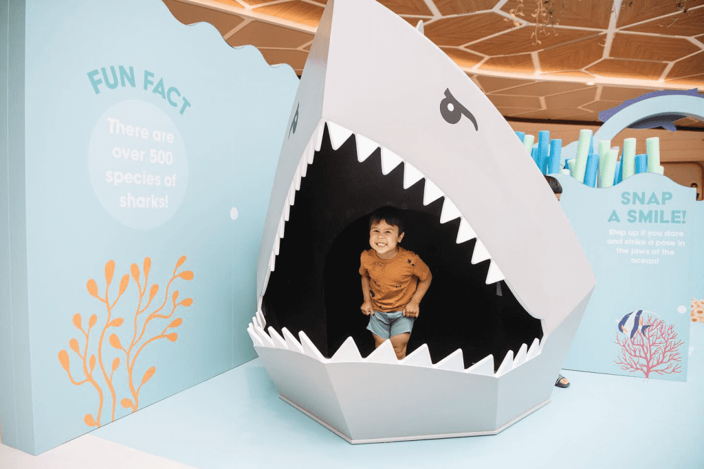 A child baring his teeth in a large shark display made from Re-Board.